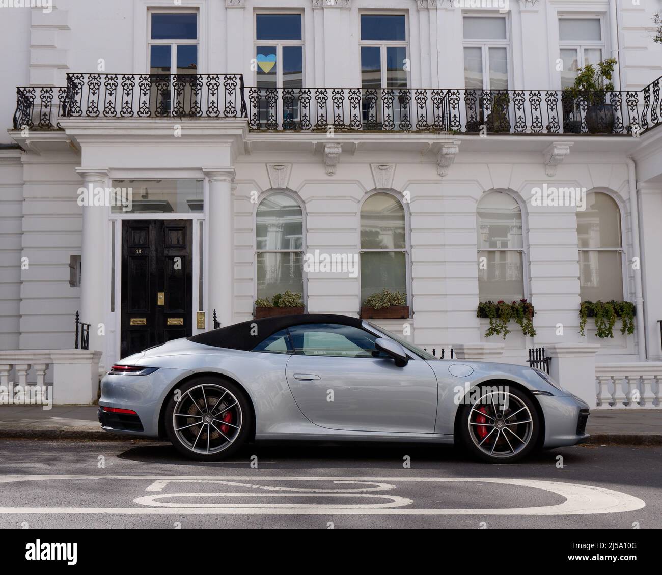 Londra, Greater London, Inghilterra, Aprile 09 2022: Porsche auto convertibile fuori da un elegante albergo a Notting Hill con un simbolo di cuore nella finestra. Foto Stock