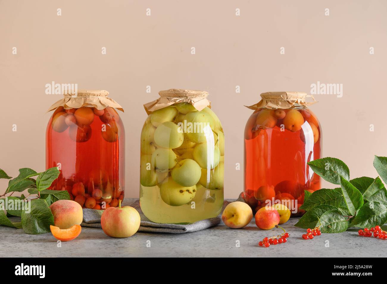 Tre frutti in scatola fatti in casa mela e ciliegia compote in grandi vasetti di vetro su tavola grigia.Estate casa coltivato raccolto e inscatolato cibo. Foto Stock