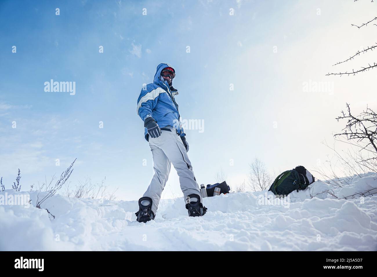 Snowboarder si erge sulle piste della montagna con uno snowboard in attrezzatura da sci Foto Stock