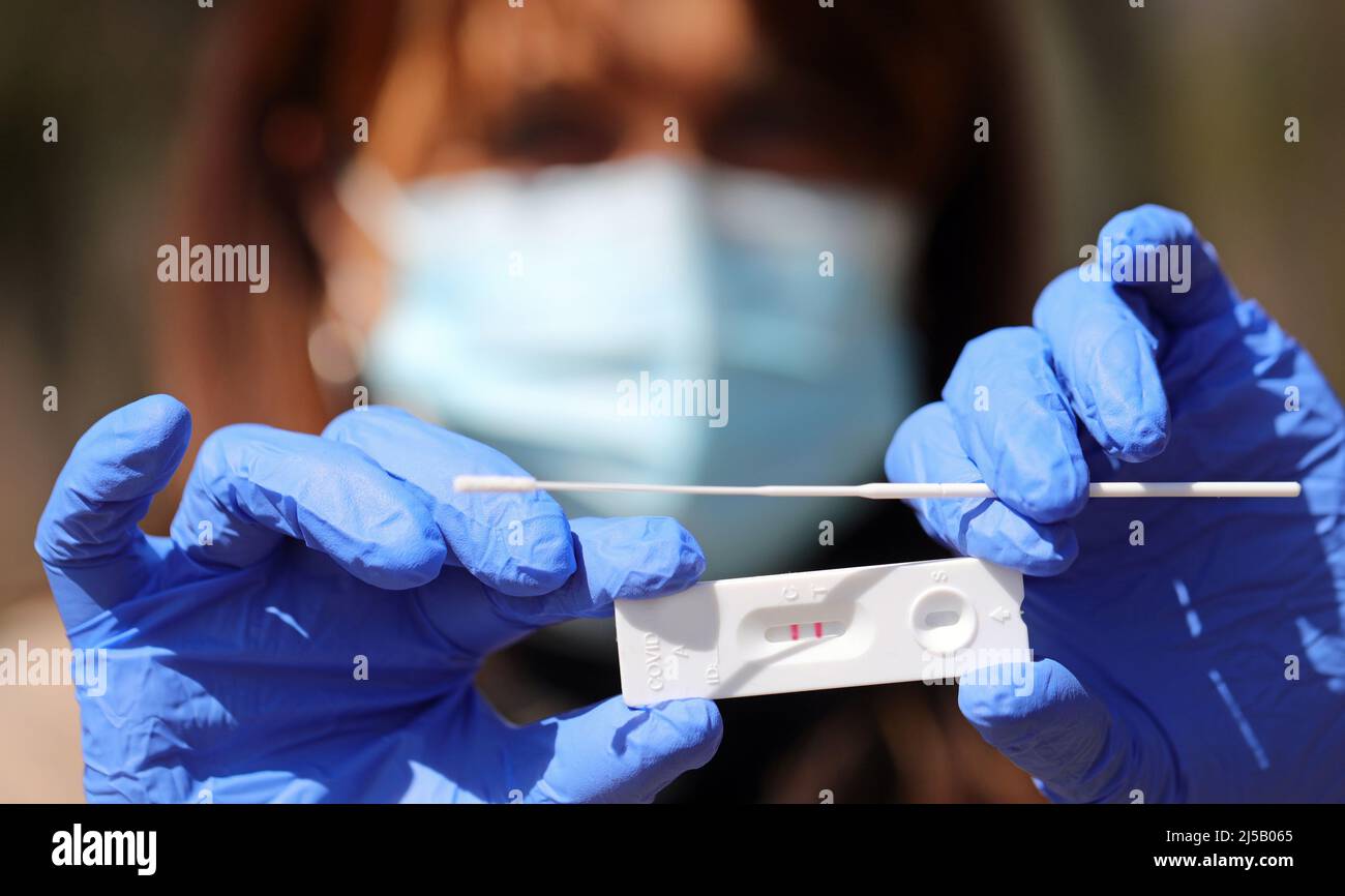 mani di medico femmina che tiene bastone di prova con due linee che indicano la positività al virus corona Foto Stock