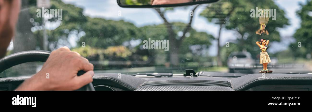 Viaggio in auto viaggio uomo guida vista dall'interno dell'auto del conducente tenendo il volante e il parabrezza con la bambola hula sul cruscotto Foto Stock