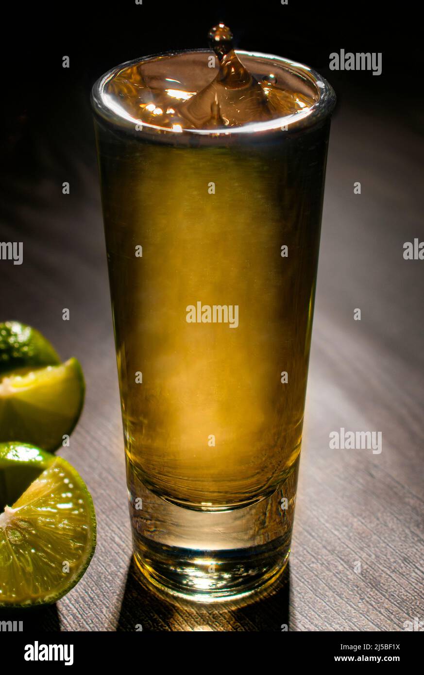 Servire una TEQUILA SHOT su un tavolo di legno con fette di limone verde sul lato, Macro fotografia Foto Stock