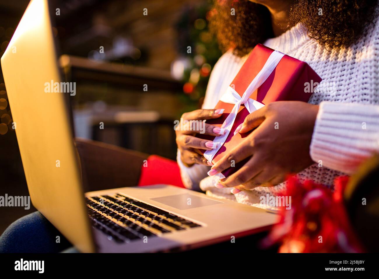 afro donna shopping online su laptop in accogliente interior.Preparing natale, bying sulle vendite invernali Foto Stock