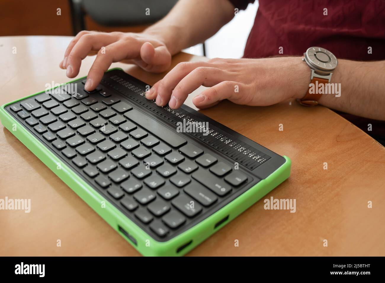 Un uomo cieco utilizza un computer con un display Braille e una tastiera per computer. Dispositivo incluso. Foto Stock