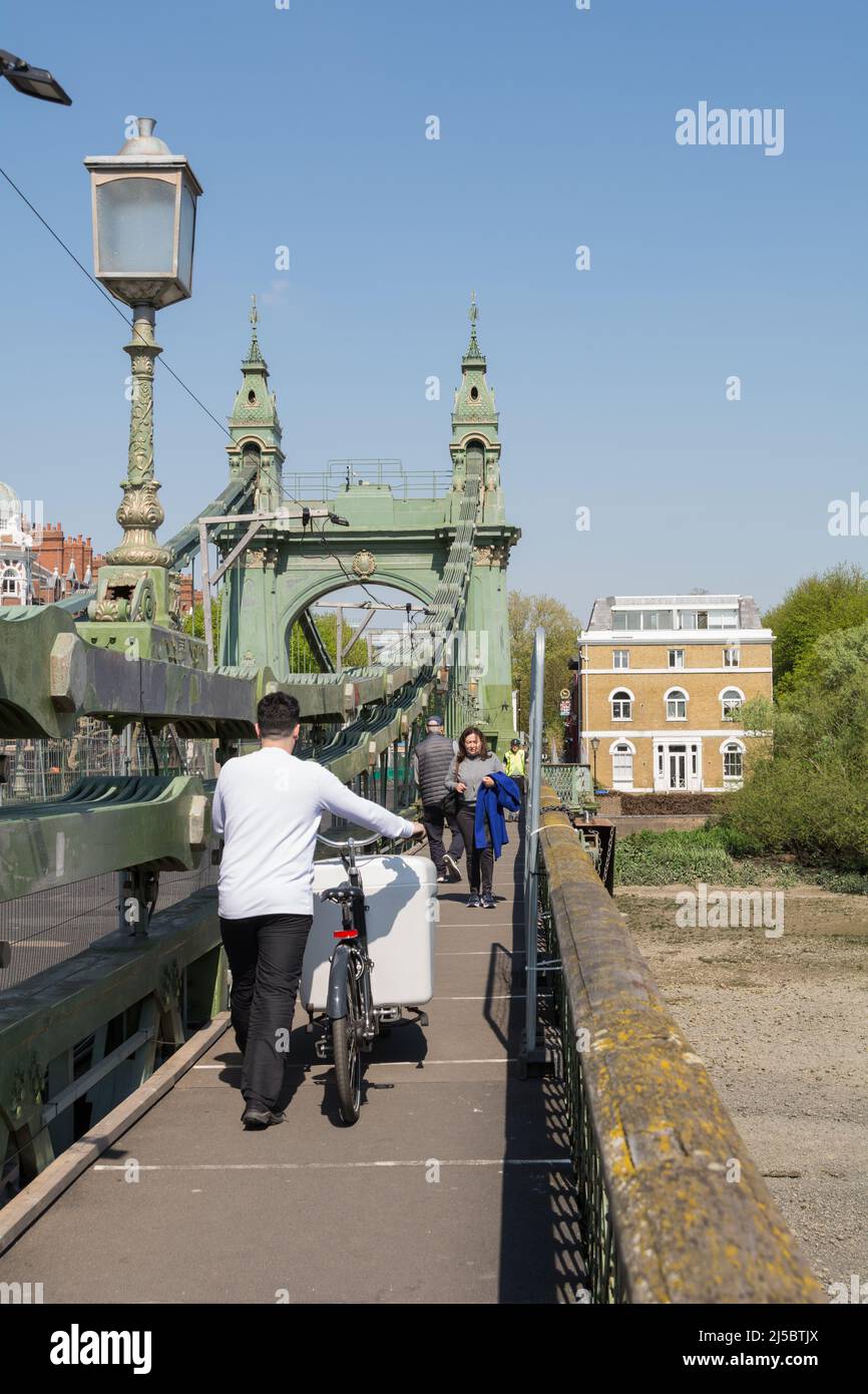 Ciclisti e pedoni che si muovono per lo spazio mentre attraversano Hammersmith Bridge a causa di riparazioni e manutenzione in corso Foto Stock