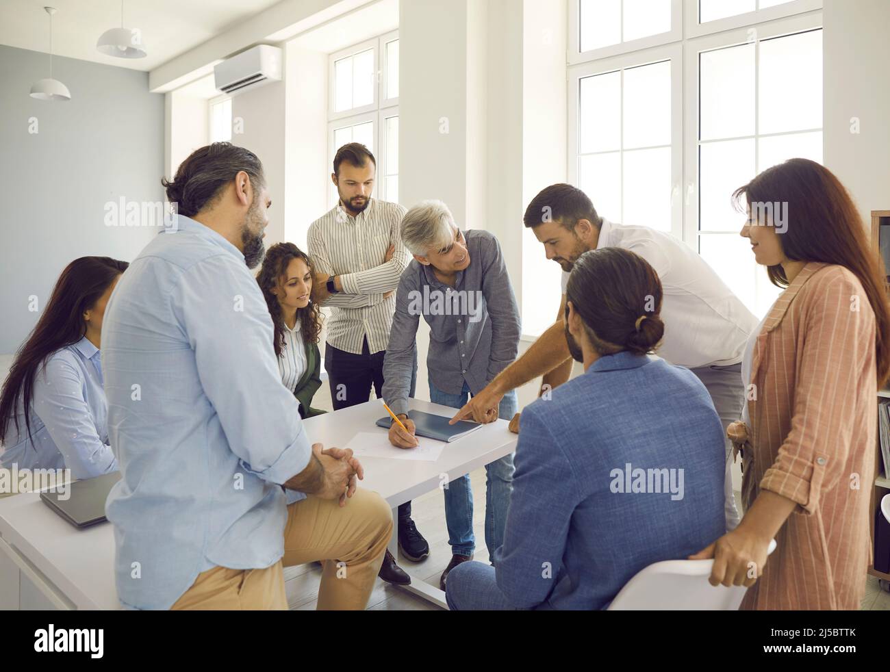 Gruppo di persone che hanno una discussione durante un incontro con un esperto business coach Foto Stock