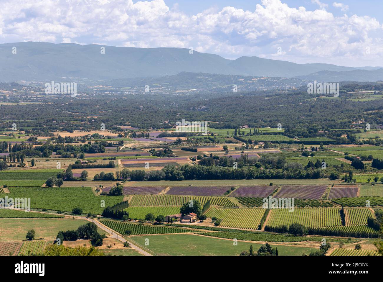 Vista panoramica della valle, piantagioni di frutta coltivata, foreste, fattorie, montagne all'orizzonte dal borgo medievale di Lacoste, Vaucluse, Francia Foto Stock