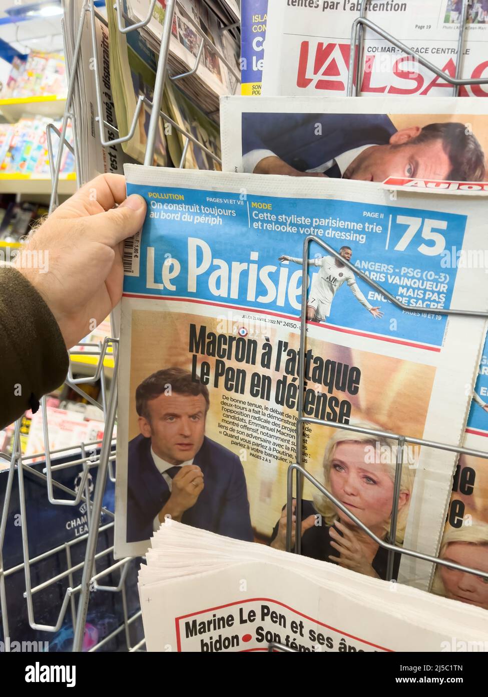 Parigi, Francia - Apr 21, 2022: POV maschio mano buy le Parisien giornale stampa titoli dopo dibattito tra Marine le Pen e il presidente francese Emmanuel Macron - elezione presidenziale del 2022 Foto Stock