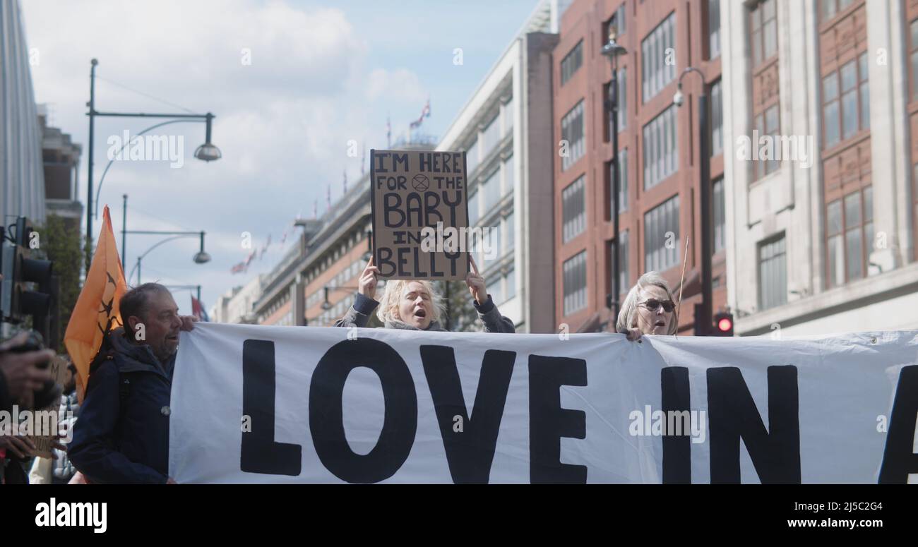 Londra, UK - 04 09 2022: Protesta del clima femminile, Extinction Rebellion, con un cartello, “sono qui per il bambino a My Belly”, bloccando Oxford Street. Foto Stock