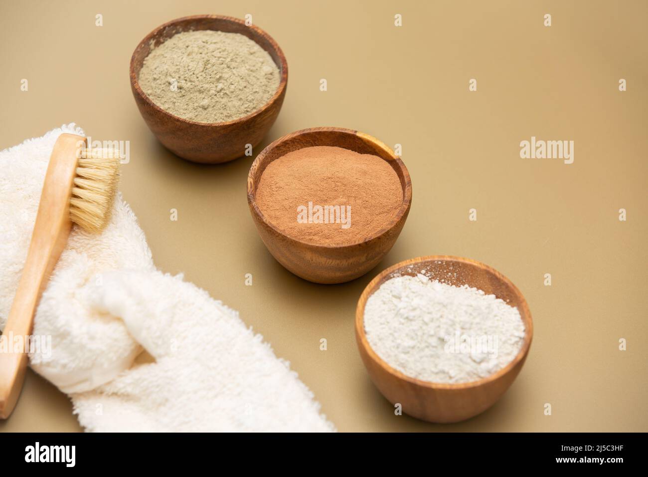 Verde organico, rosso, bianco maschera argilla in ciotole di legno con morbido bendaggio spugna e bambù e spazzola di capra capelli su sfondo beige. Cura della pelle domestica Foto Stock