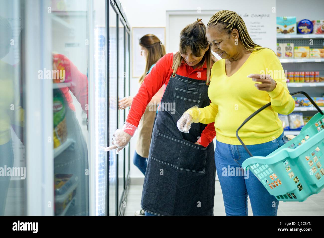 Venditore che aiuta la donna ispanica a scegliere i prodotti Foto Stock