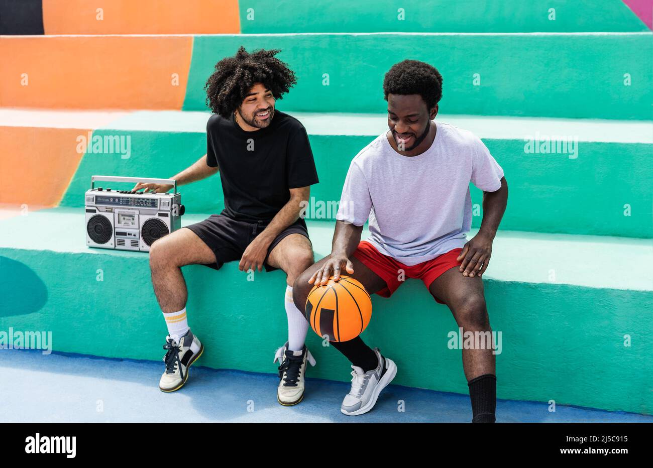 Happy Afro American amici ascoltare musica all'interno del campo da basket con stereo boombox d'epoca - Urban Street People lifestyle Foto Stock