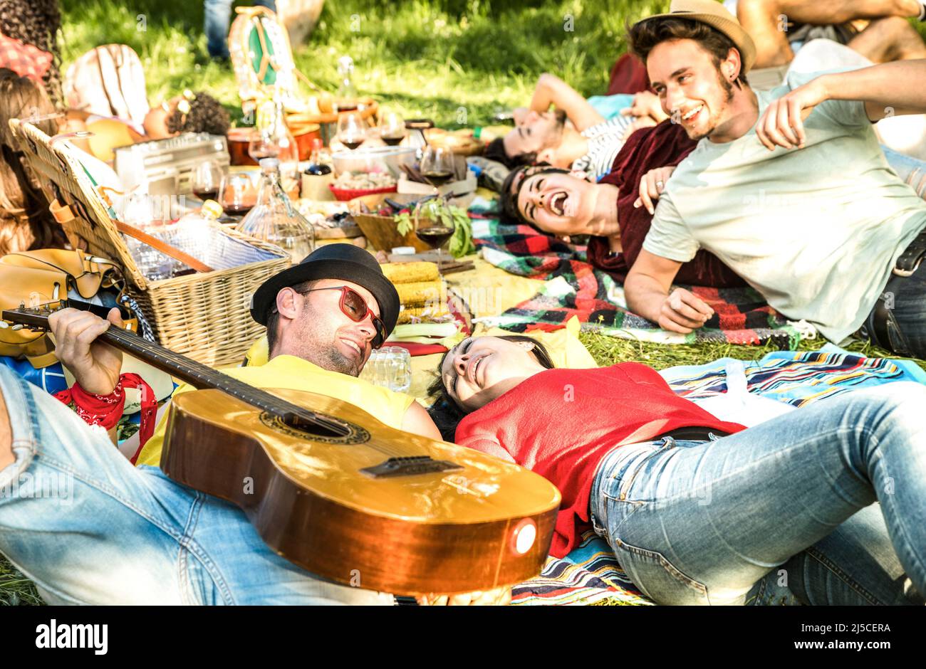 Coppia in amore con gli amici gruppo divertirsi a barbecue picnic con chitarra d'epoca - giovani millennial godersi il tempo di primavera insieme a ba Foto Stock