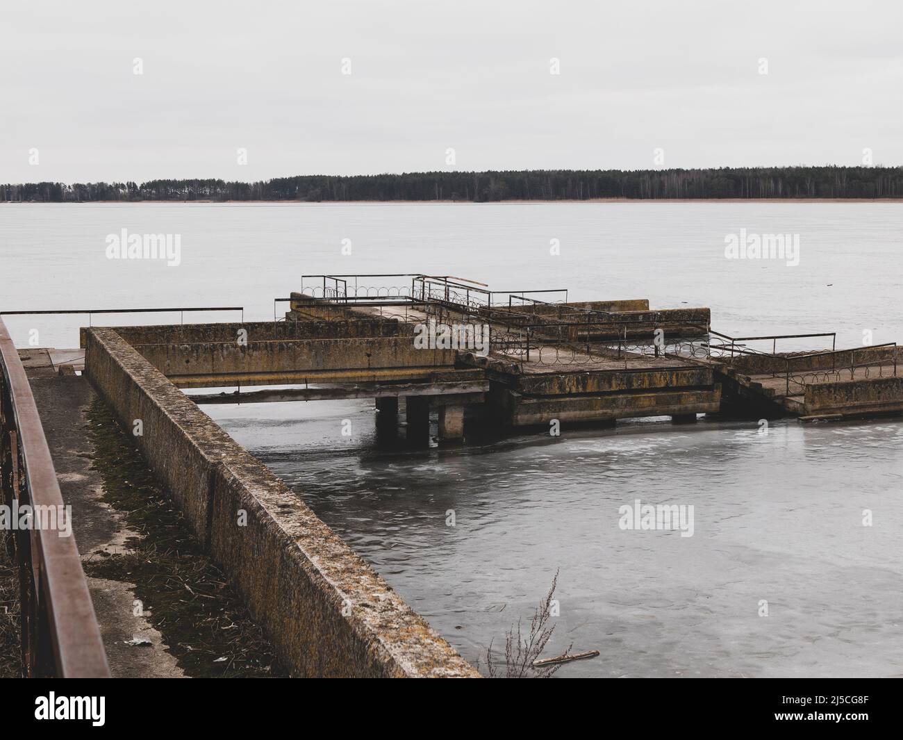 Un paesaggio monocromatico e sobrio con un molo desolato in inverno semivuinizzato. Senso di malinconia e solitudine Foto Stock
