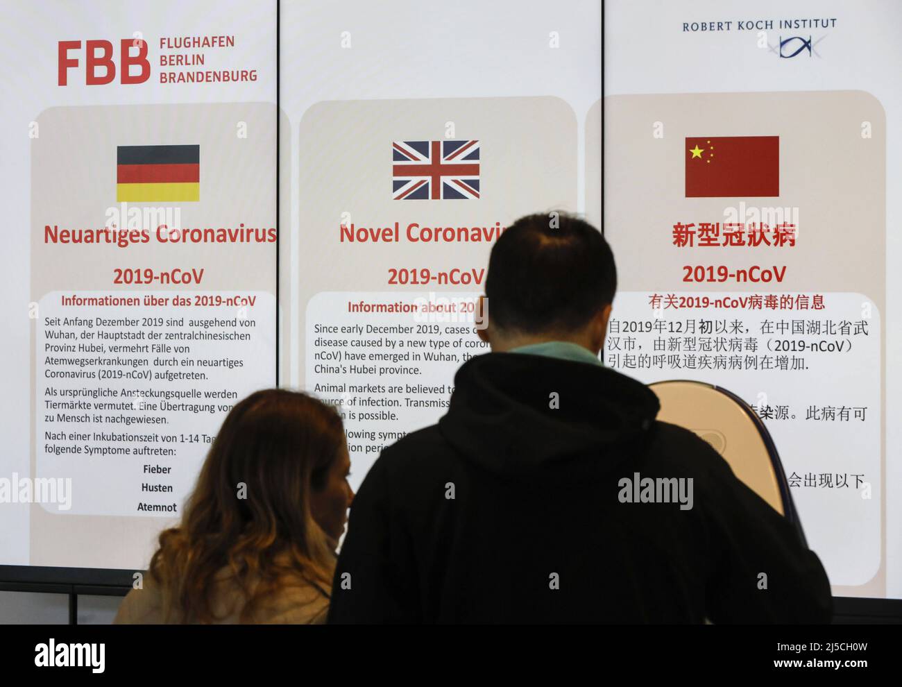 I passeggeri dell'aereo guardano a un'bacheca informativa del Robet Koch Institute sul coronavirus all'aeroporto di Tegel. [traduzione automatizzata] Foto Stock