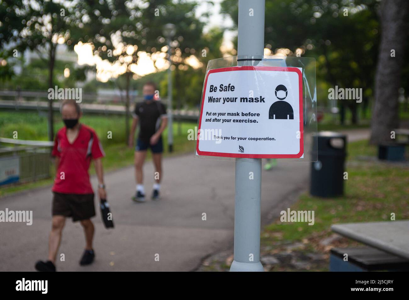 15 maggio 2020, Singapore, Repubblica di Singapore, Asia - Un uomo che  indossa una guardia del boccaglio cammina oltre un cartello su Covid-19 nel  Parco Bishan-Ang Mo Kio, che mette in evidenza