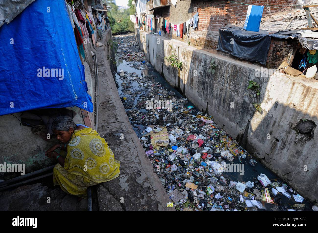 07.12.2011, Mumbai, Maharashtra, India, Asia - circondato da edifici e semplici hovels, un fiume stretto traboccante di rifiuti domestici e rifiuti di plastica nel distretto di Slum di Mumbai di Dharavi. Il distretto di Dharavi è situato nel cuore della metropoli indiana di Mumbai ed è una delle baraccopoli più grandi del mondo, con una popolazione stimata di 500.000 - 1 milioni di persone. [traduzione automatizzata] Foto Stock