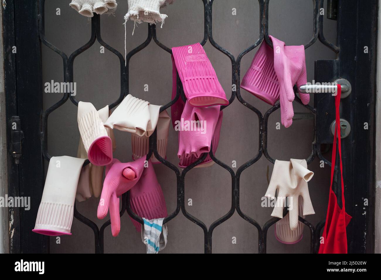 07.07.2017, Singapore, Repubblica di Singapore, Asia - guanti di gomma umidi appesi ad asciugare su una porta barred nel quartiere Chinatown della città. [traduzione automatizzata] Foto Stock