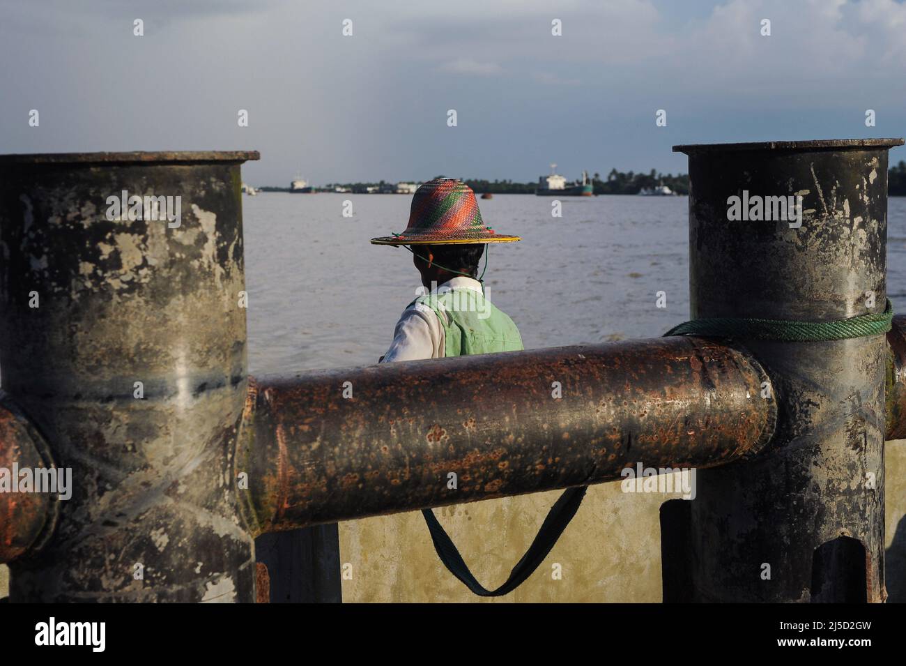 31.10.2013, Yangon, Myanmar, Asia - Un tassista di fiume attende i passeggeri sulle rive del fiume Yangon (fiume di Claing) ad un molo tra arrugginiti. [traduzione automatizzata] Foto Stock