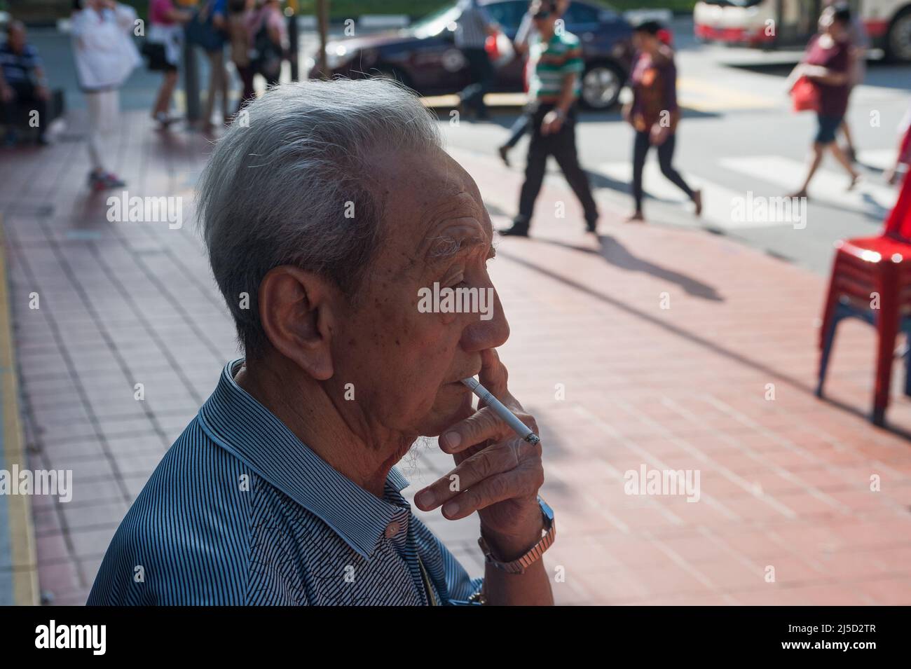 07/16/2017, Singapore, Repubblica di Singapore, Asia - un vecchio uomo si trova sul lato della strada a Chinatown e fuma una sigaretta felicemente. [traduzione automatizzata] Foto Stock
