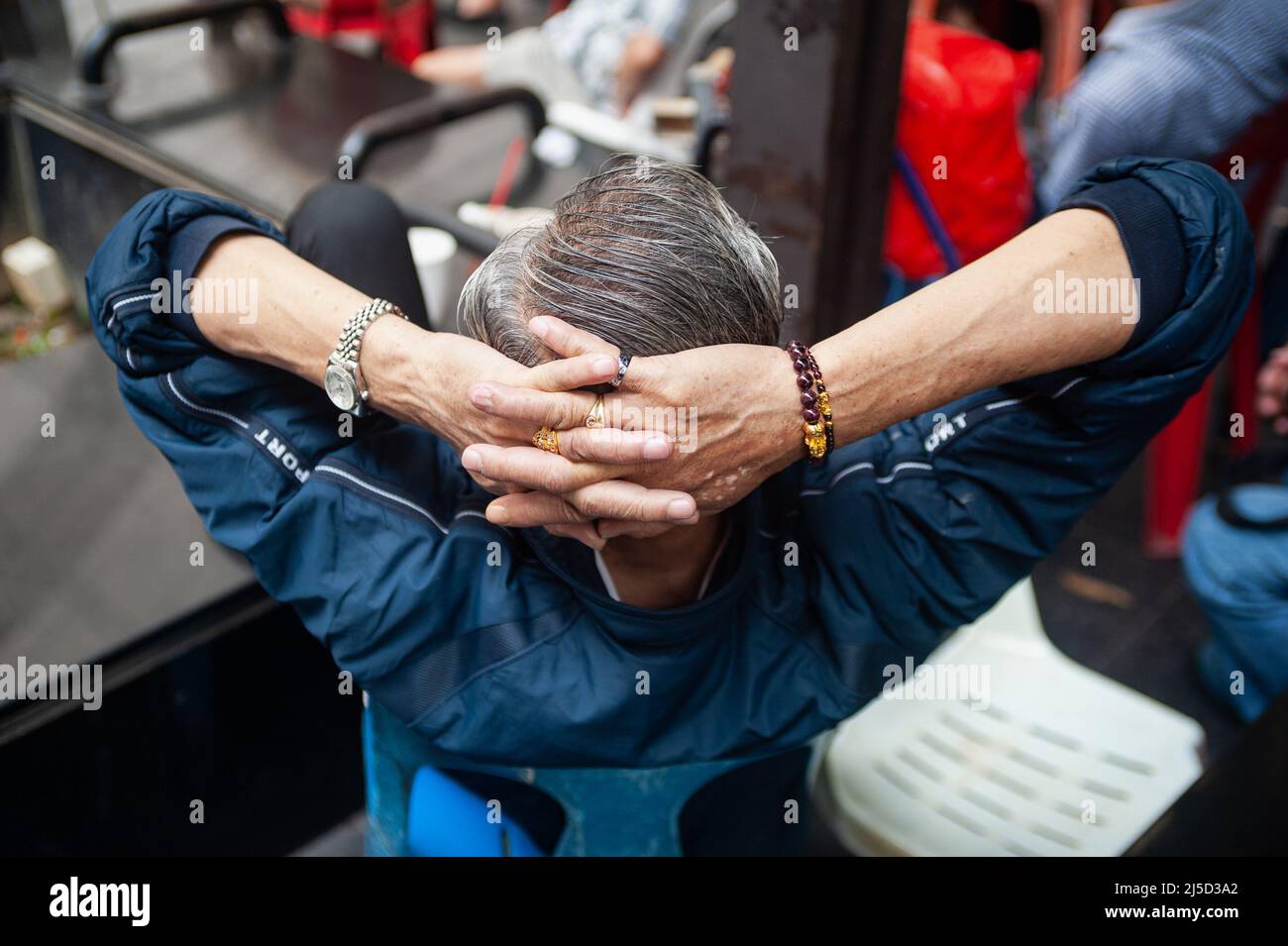 24 febbraio 2019, Singapore, Repubblica di Singapore, Asia - il primo piano mostra le mani intrangolate dietro la testa di un anziano a Chinatown indossando un orologio da polso, un braccialetto e diversi anelli sulle sue dita. [traduzione automatizzata] Foto Stock