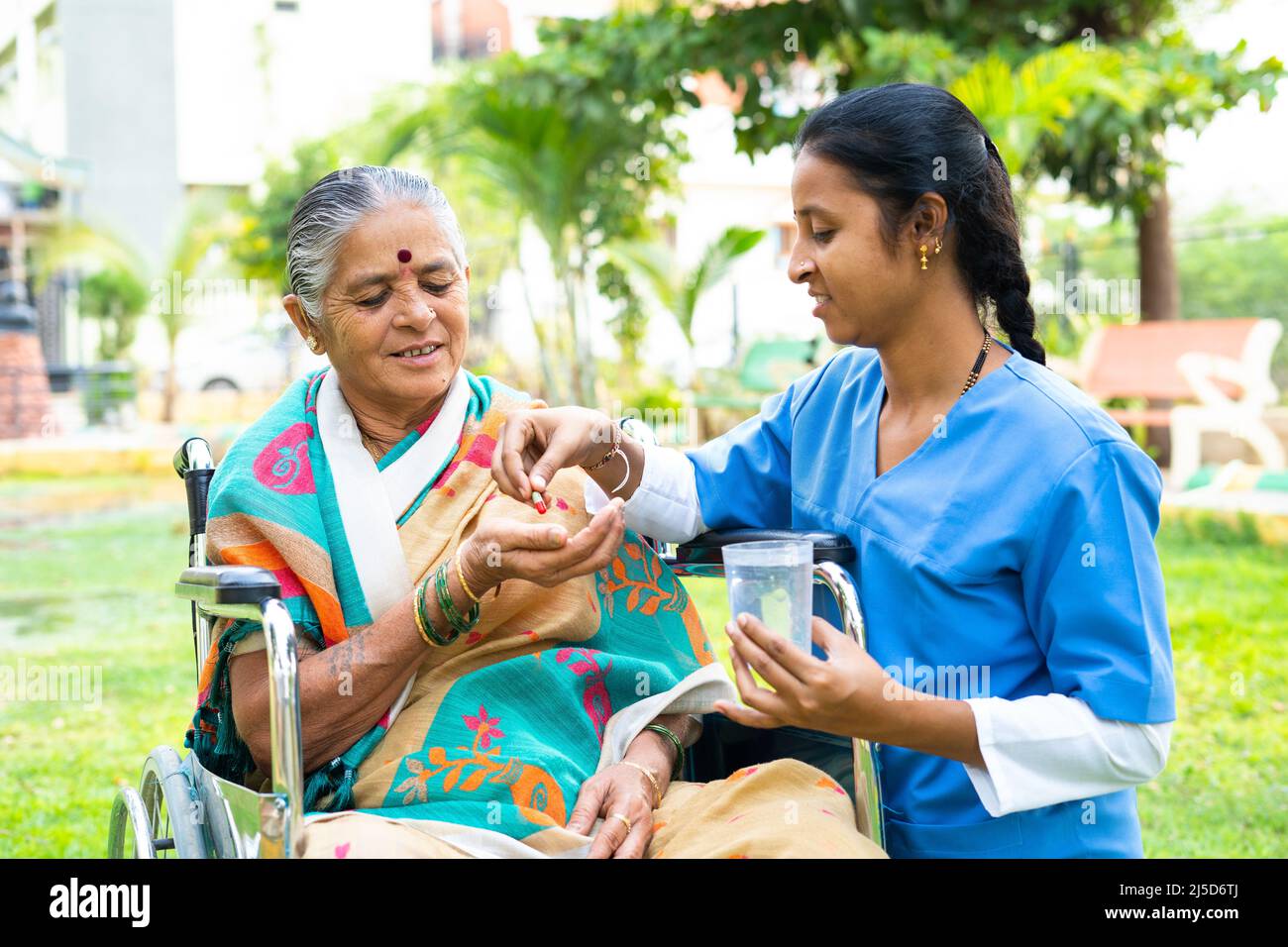 Infermiera che dà compresse o pillole alla donna anziana su sedia a rotelle con disabilità - concetto di medicare, custode e trattamento Foto Stock