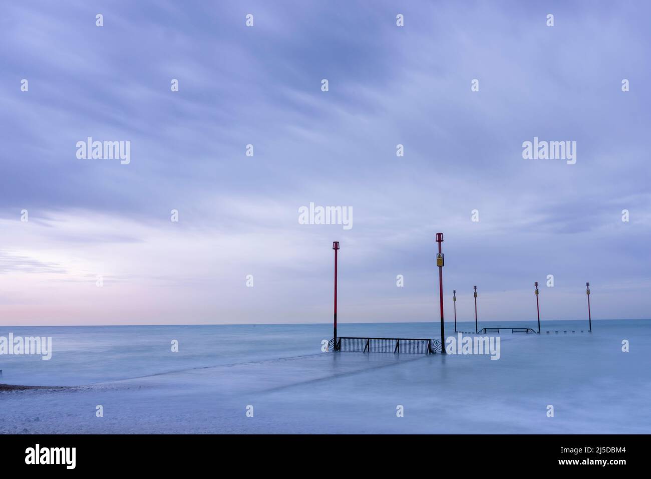 Tubi di scarico e pali di segnalazione in un mare calmo all'alba Foto Stock