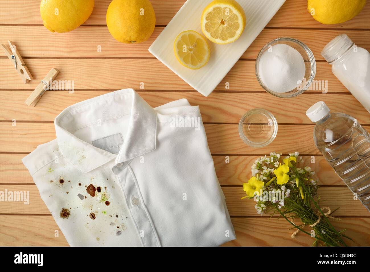 Confronto e concetto di pulizia e lavaggio dei vestiti con prodotti naturali ed ecologici con camicia semi sporca e semi pulita su legno Foto Stock