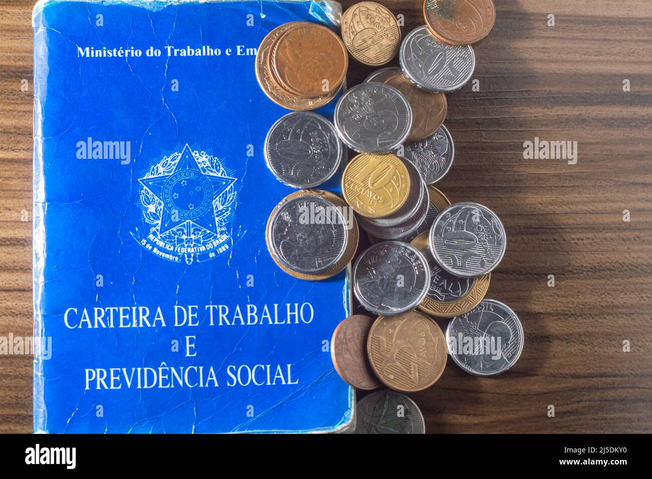 Traduzione: Repubblica Federativa del Brasile, Ministero del lavoro. Scheda di lavoro (Carteira de trabalho) accanto alle monete reali brasiliane, denaro brasiliano. Foto Stock