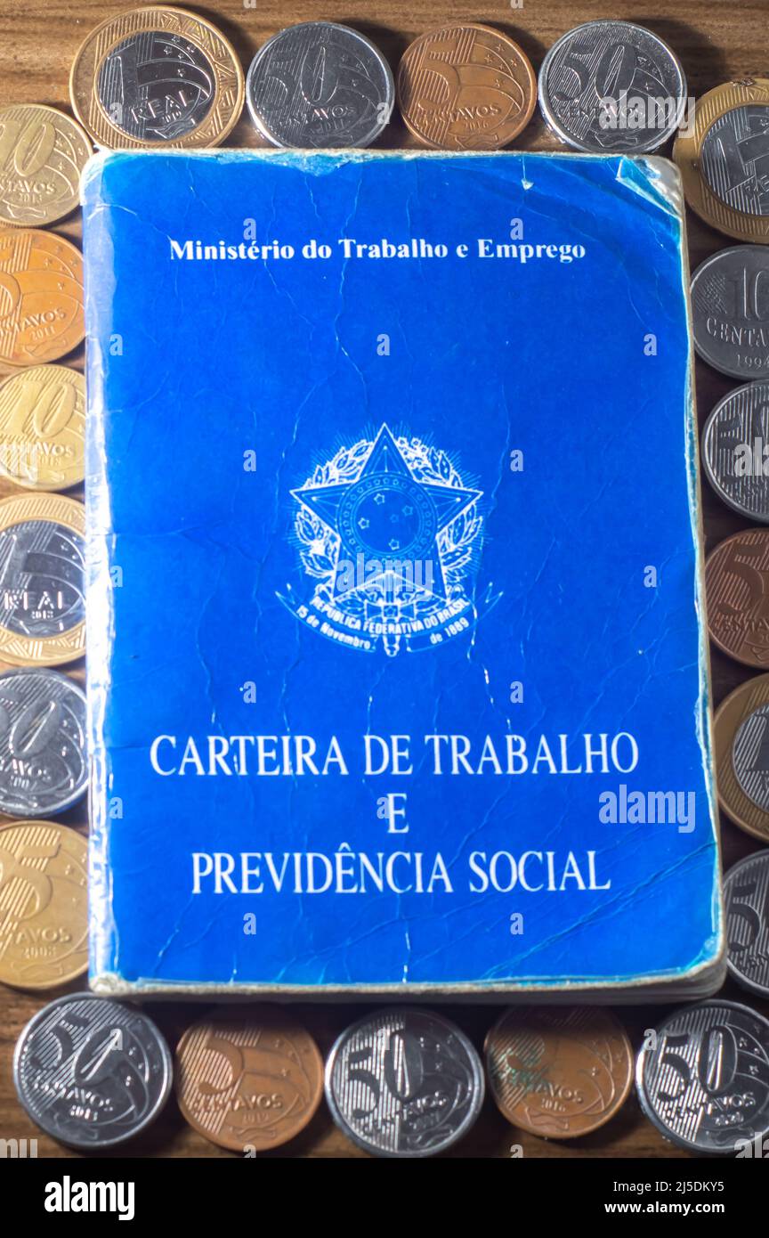 Traduzione: Repubblica Federativa del Brasile, Ministero del lavoro. Scheda di lavoro (Carteira de trabalho) accanto alle monete reali brasiliane, denaro brasiliano. Foto Stock