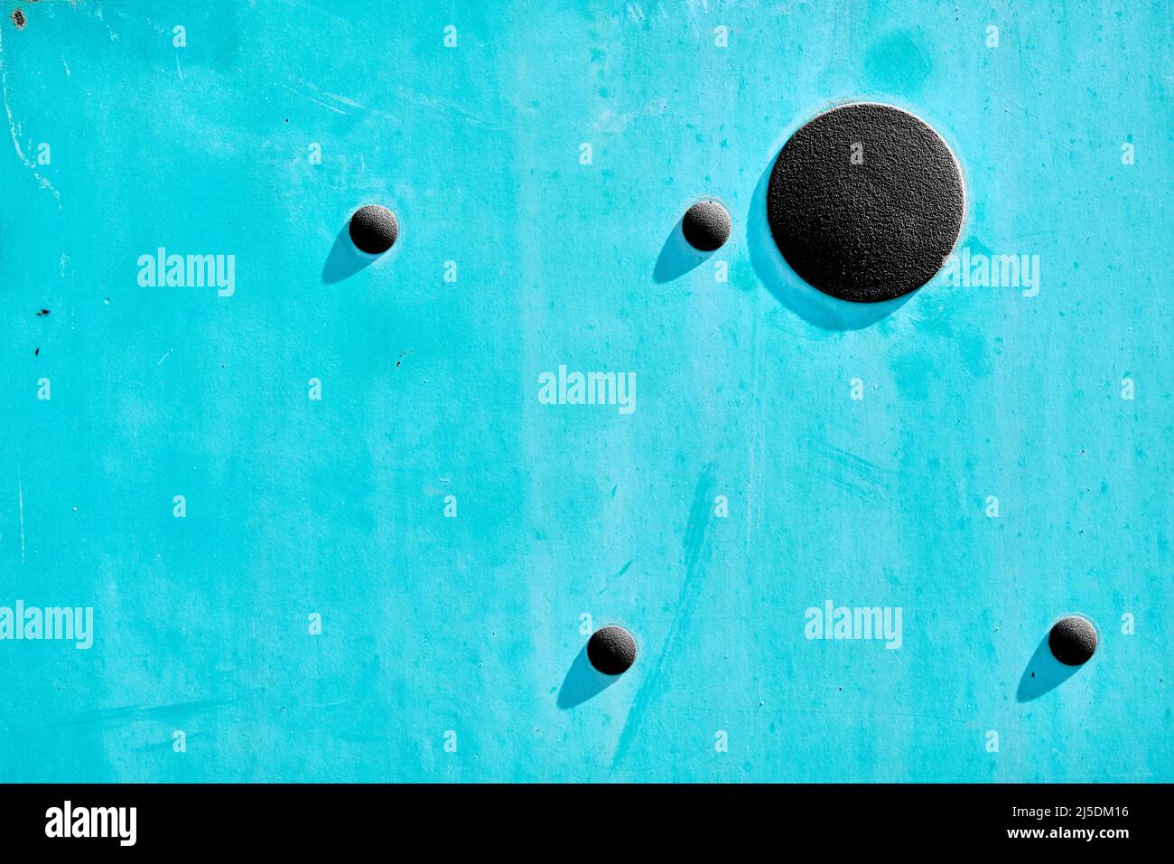 Astratto di metallo turchese snocciolato e nascosto dalla vita all'esterno, con 4 piccoli cerchi di gomma e più grande cerchio nero che fondano una superficie di ombre poco profonda Foto Stock