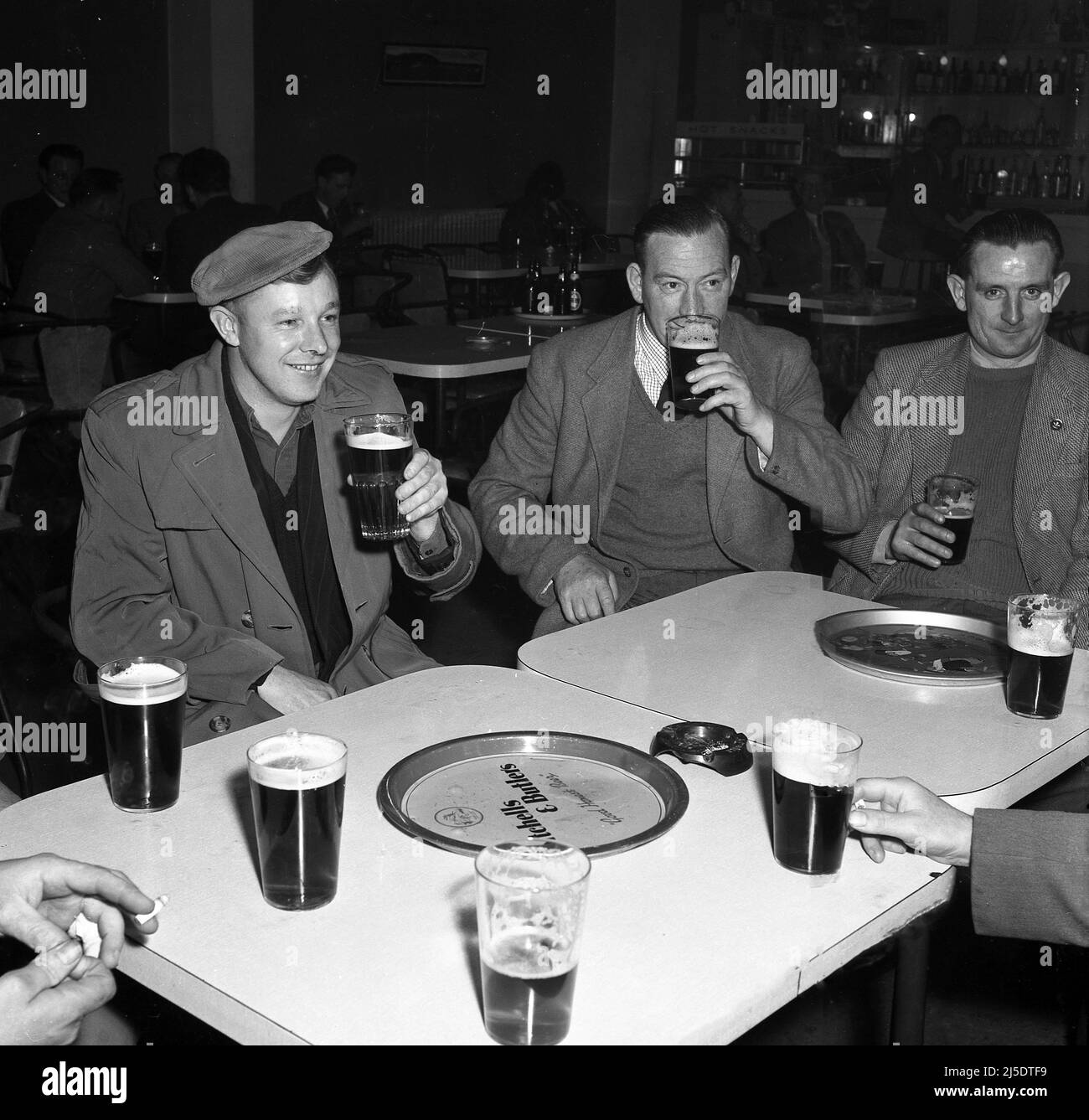 1950s, storico, tre operai gallesi dell'acciaio che si siedono insieme nel randello sociale o nel bar di lavori godendo di alcune pinte dopo un cambiamento duro della giornata, Abbey Works, Port Talbot, Galles, Regno Unito. Foto Stock