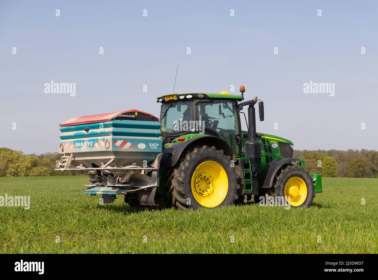 Coltivatore che guida il trattore e irrorazione di fertilizzante in un campo nella primavera del 2022. Hertfordshire Regno Unito Foto Stock