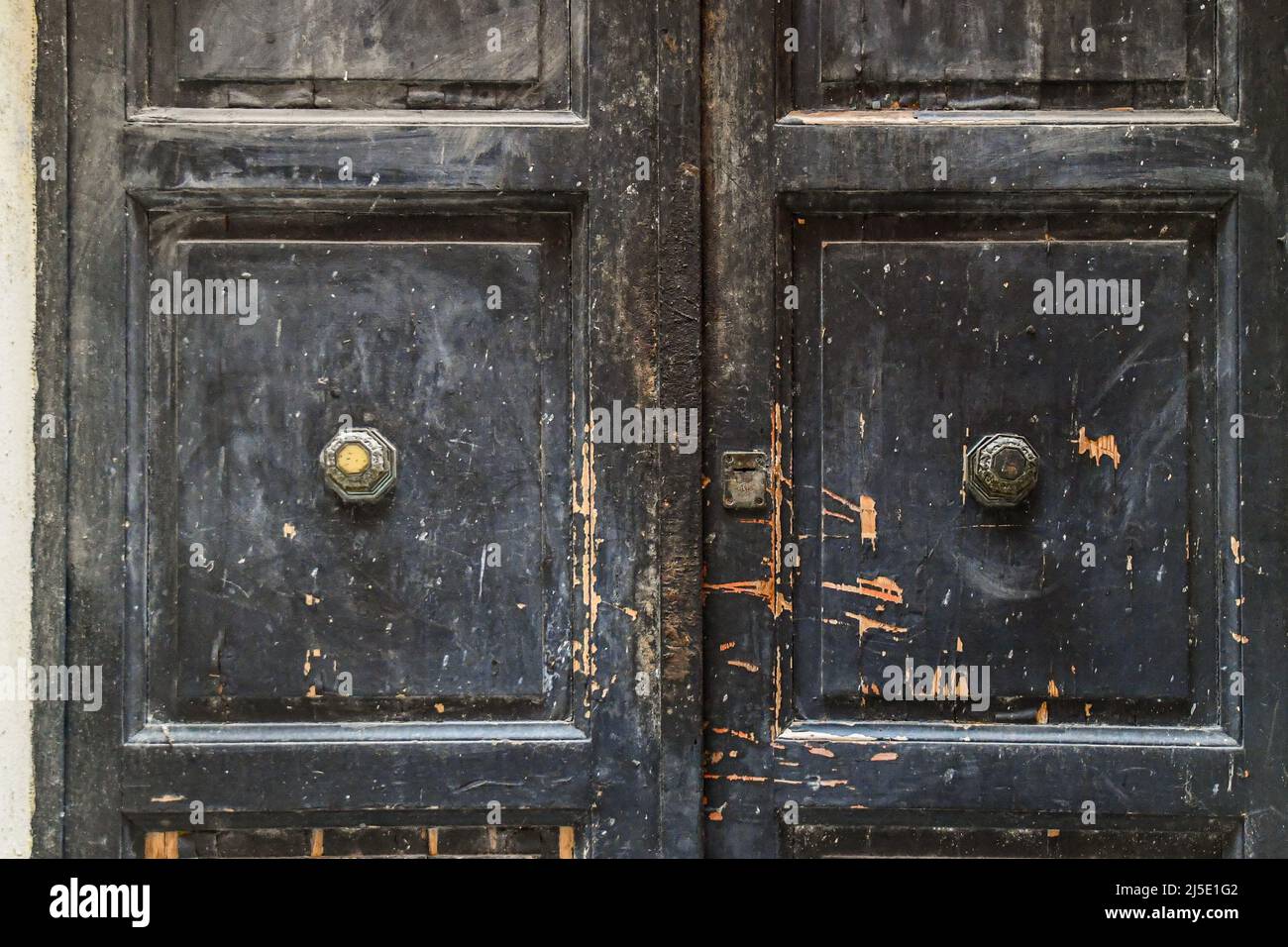 Primo piano di una porta in legno nero intemperiato con maniglie in metallo e legno graffiato, Italia Foto Stock