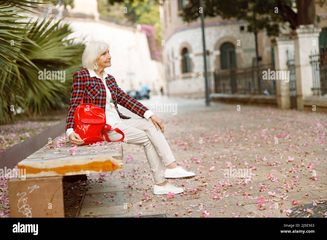 Donna anziana felice che cammina in città Foto Stock