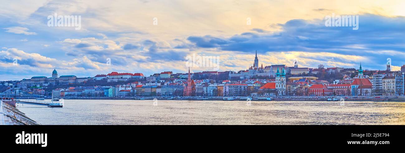 Il luminoso cielo viola sopra gli edifici storici del distretto di Buda, come il Bastione dei pescatori, la Chiesa di Mattia, il Castello di Buda, visto dietro il Danubio, Buda Foto Stock