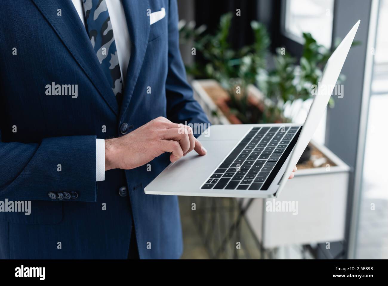 vista ritagliata di un uomo d'affari che utilizza un laptop mentre si trova in ufficio Foto Stock