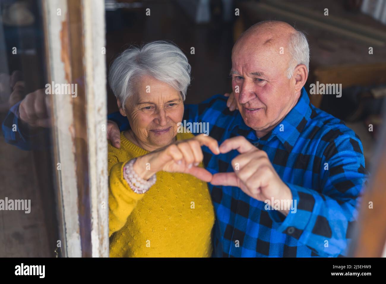 lunga e felice - coppia anziana carina che fa sentire la forma con le dita medio primo piano da sopra il concetto di supporto della gente anziana del salotto. Foto di alta qualità Foto Stock