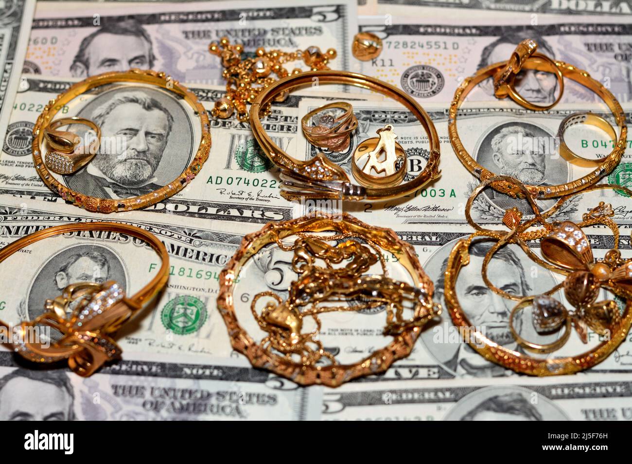 Un set di accessori d'oro di anelli, catene e bracciali su dollari  americani banconote di diversi valori, concetto di valore d'oro, acquirente  di gioielli, p Foto stock - Alamy