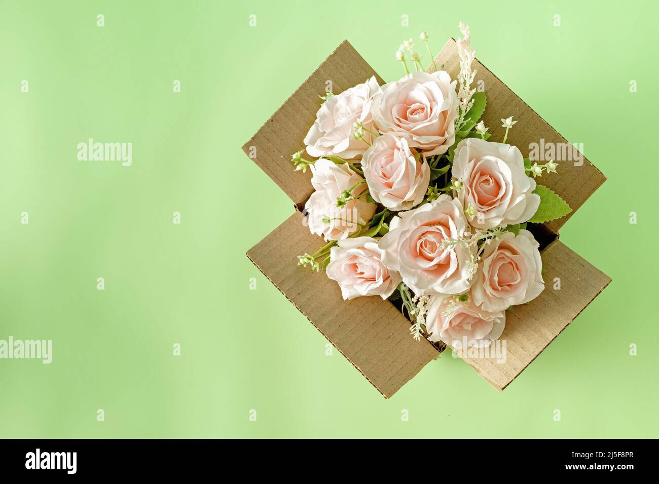 Un bel bouquet fiorente di rose rosa in una scatola di cartone di consegna pacchi e spazio copia. Concetto di vacanza regalo e amore e servizio logistico. Foto Stock