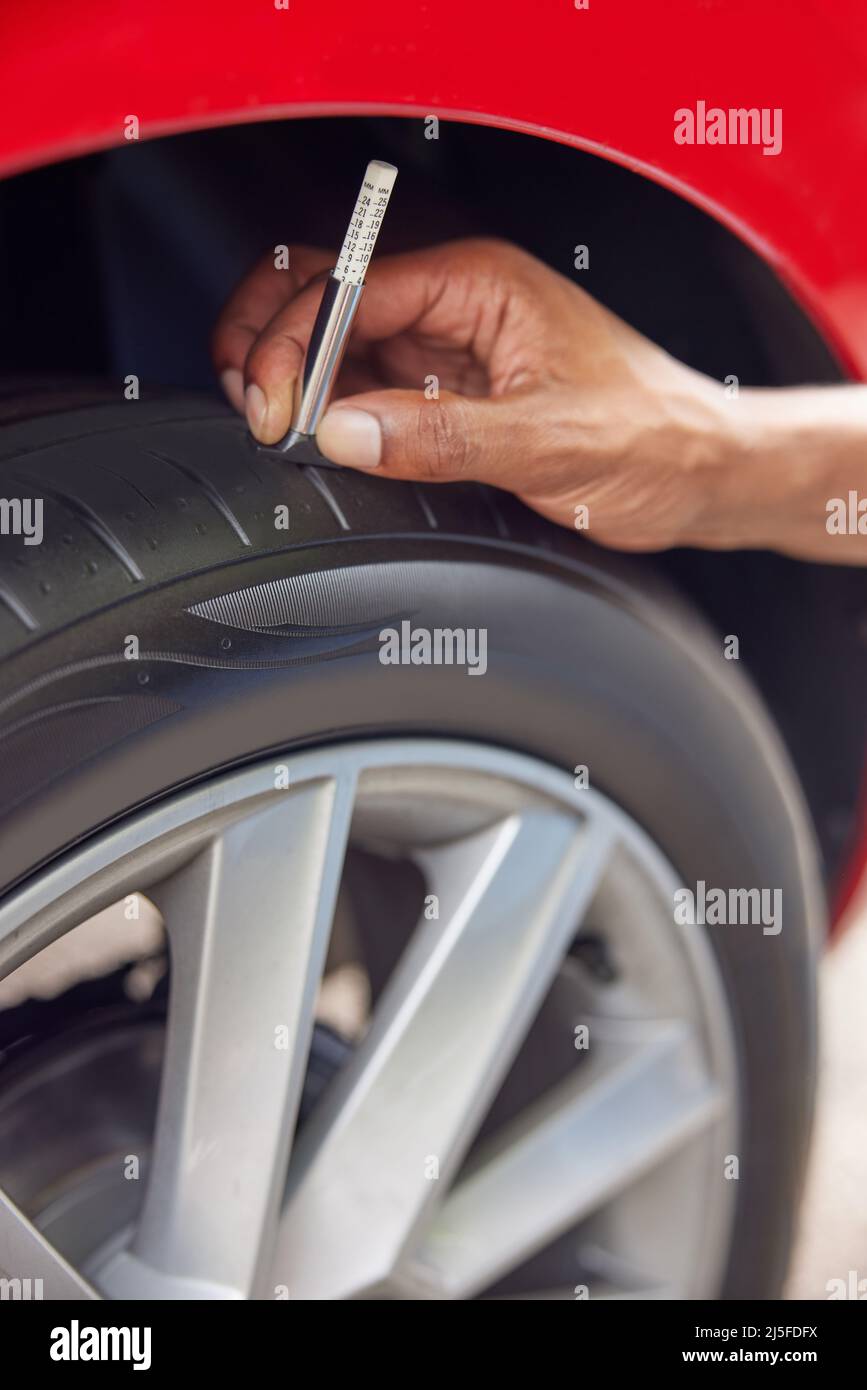 Close-Up dell uomo il controllo sul battistrada di pneumatici vettura con manometro Foto Stock