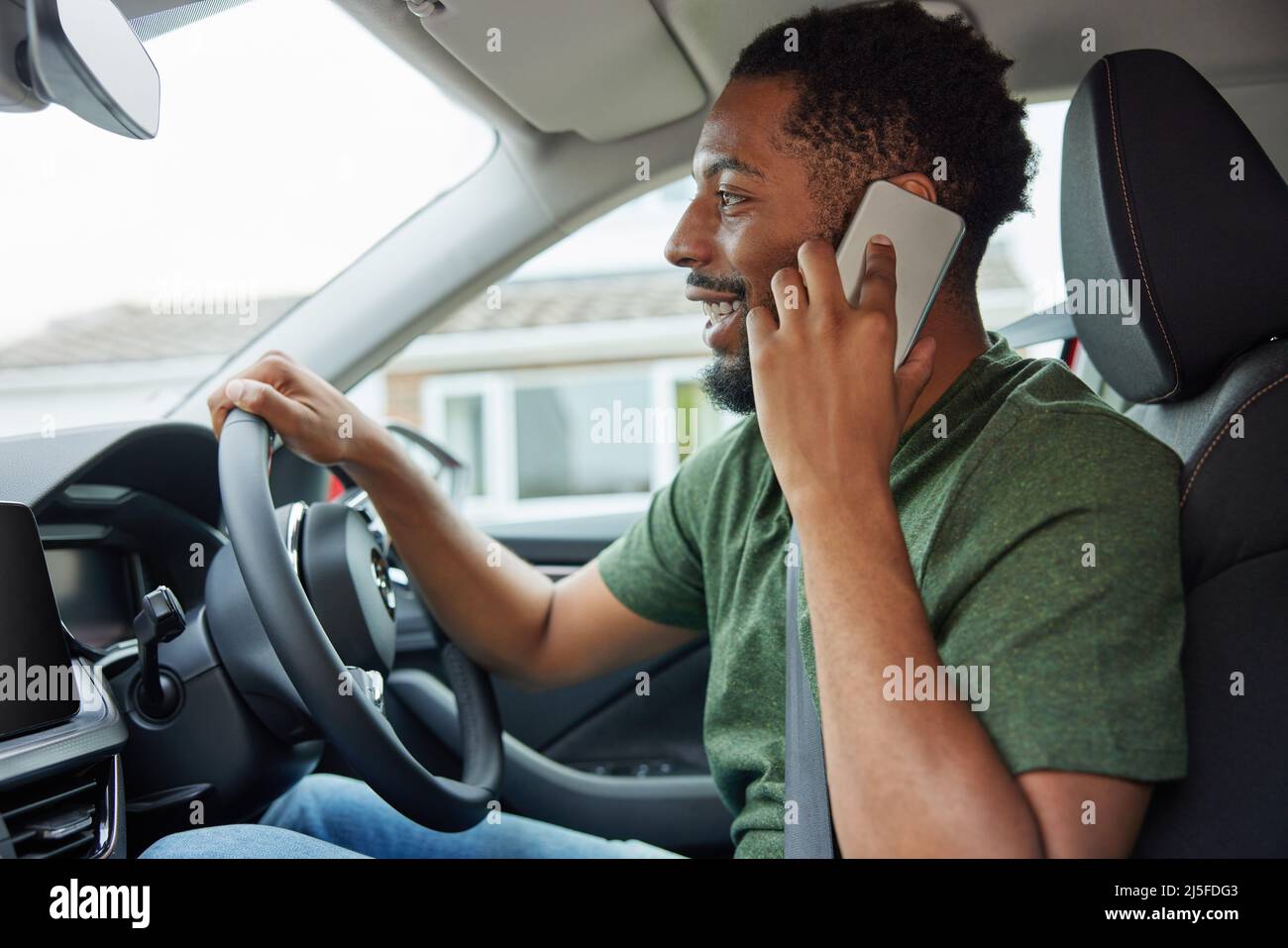 Uomo che parla al telefono cellulare mentre guida l'auto Foto Stock