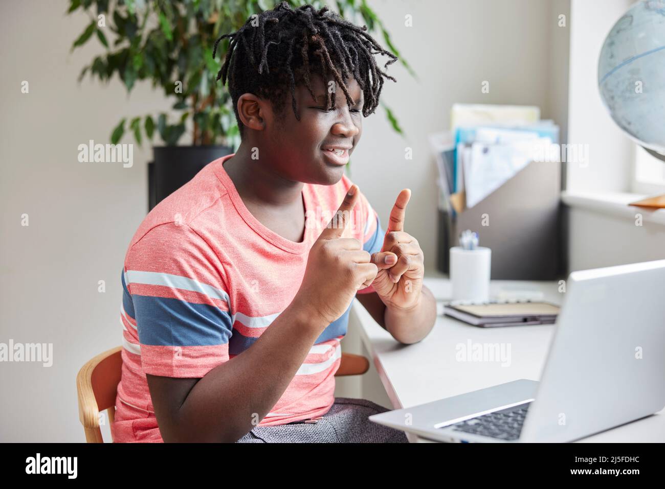 Ragazzo adolescente che ha una conversazione utilizzando il linguaggio dei segni sul portatile a casa Foto Stock