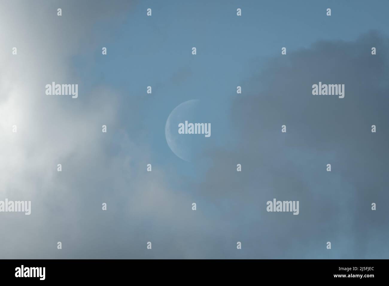 Luna crescente in pelo mattutino, tra nuvole chiare e scure. Foto Stock