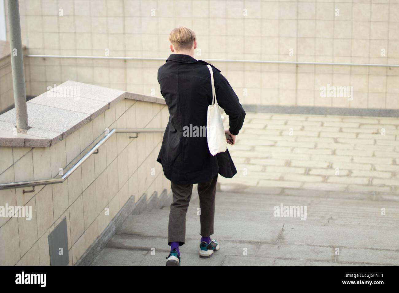 Il ragazzo sta scendendo le scale. Attraversamento pedonale. Un uomo va al lavoro. Un abitante della città sulla strada. Foto Stock