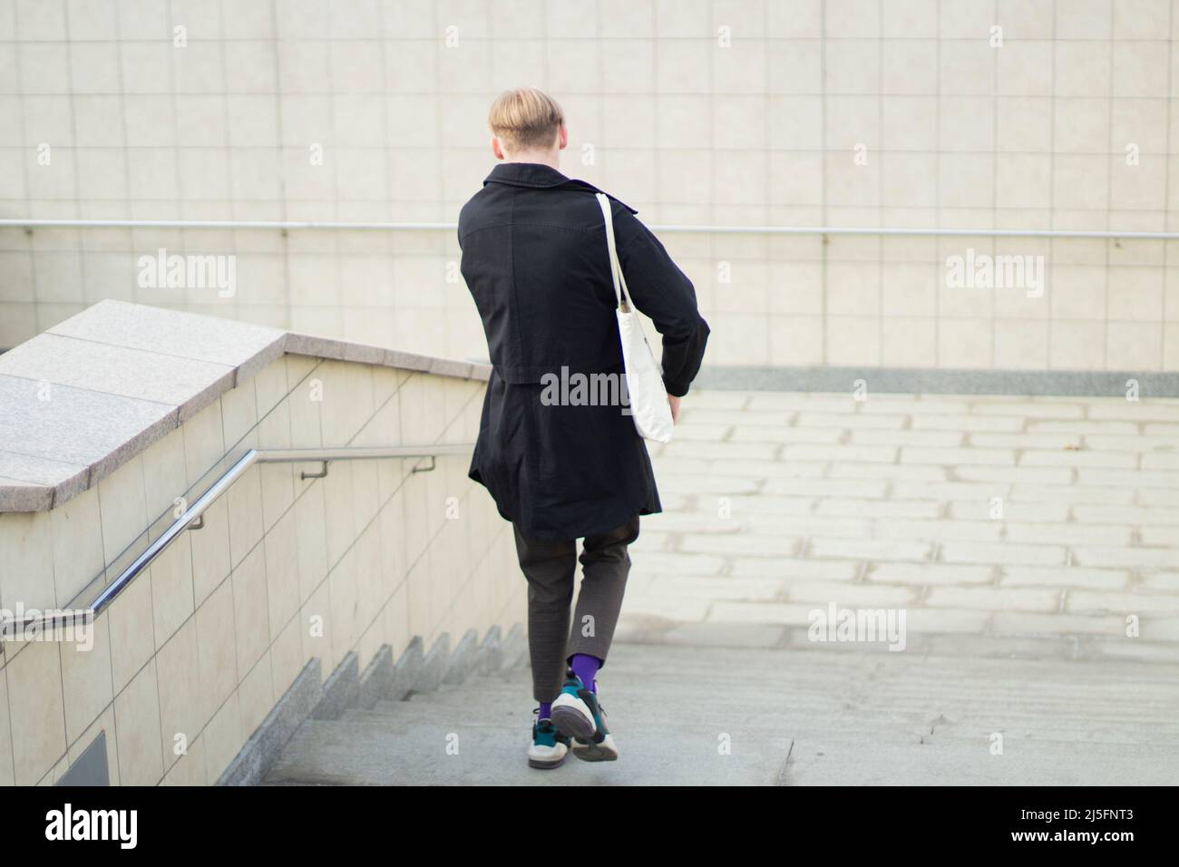Il ragazzo sta scendendo le scale. Attraversamento pedonale. Un uomo va al lavoro. Un abitante della città sulla strada. Foto Stock
