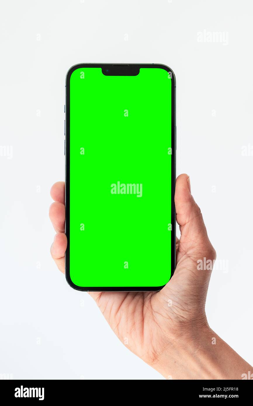 Chiudi la mano tenere il telefono isolato su bianco, smartphone verde schermo vuoto Foto Stock