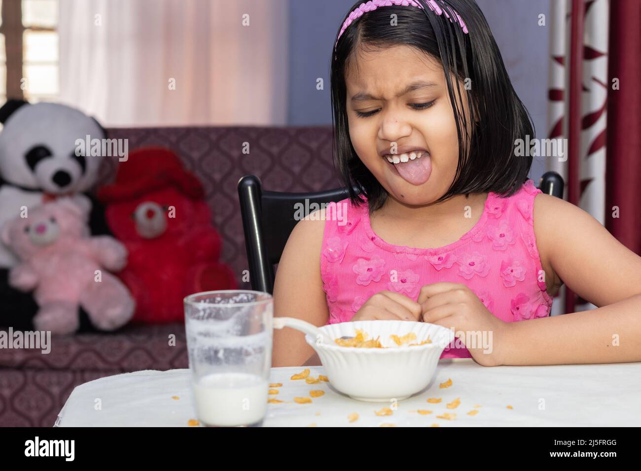Una bambina indiana con pasto incompleto di cornflakes e latte che mostra dissimile Foto Stock