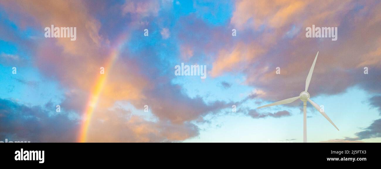 Concetto di energia rinnovabile: Turbina eolica con arcobaleno in cielo. Pulito, economico, elettricità, riscaldamento globale, cambiamento climatico, emissioni nette zero Foto Stock