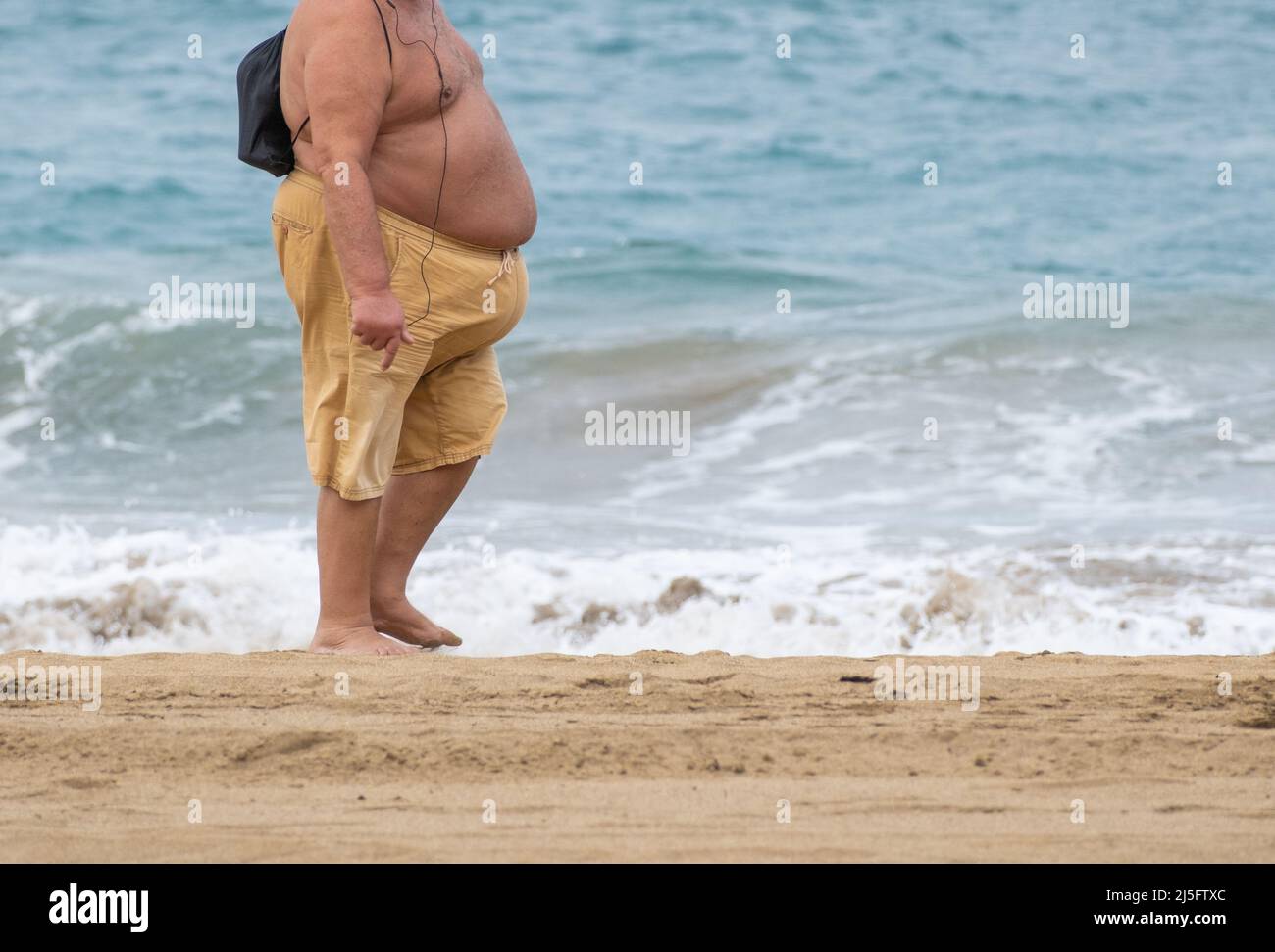 Sovrappeso, uomo obeso che cammina sulla spiaggia. Foto Stock